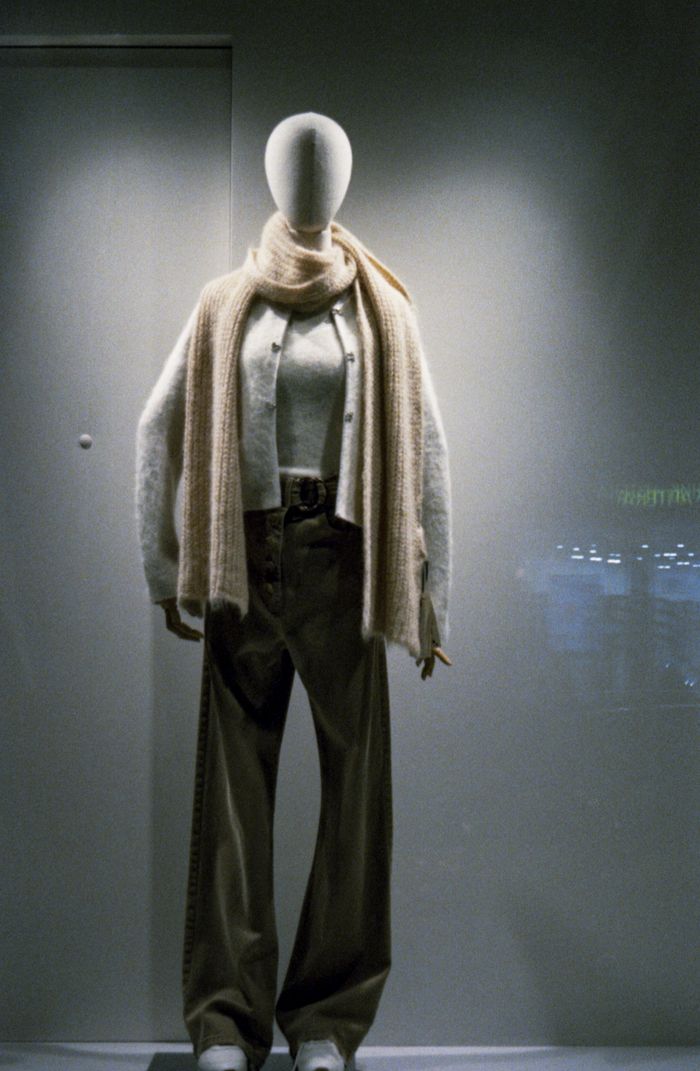 Mannequin wearing stylish winter outfit in a store window display with soft lighting.